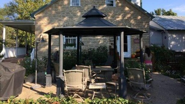 A stone house with a covered patio area, outdoor furniture, and a small garden. - Stone Haus Bed & Breakfast (Hermann)