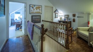 A cozy living room with a wooden staircase, a world map, and a fire extinguisher. - Stone Haus Bed & Breakfast (Hermann)