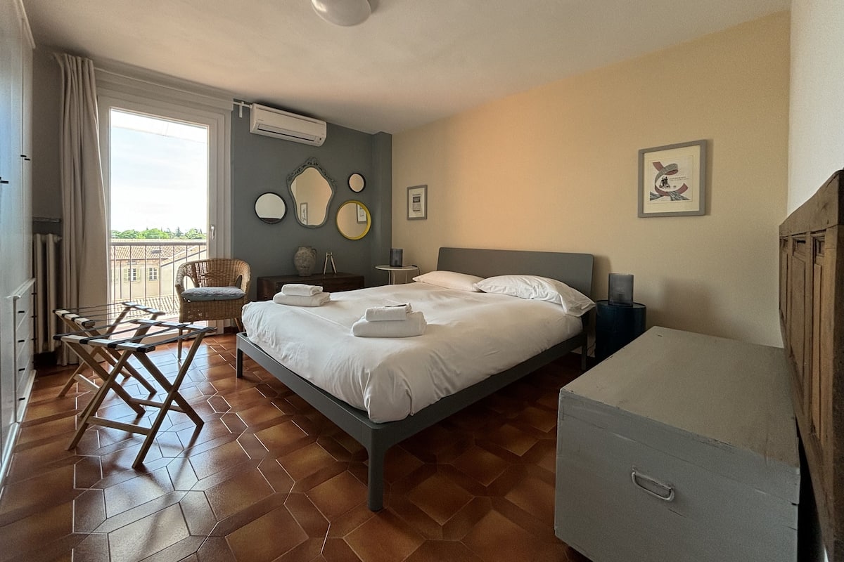 A bedroom with a bed, a chair, a dresser, and a window with curtains.