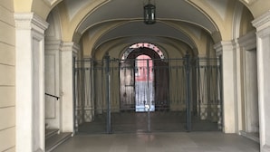 An interior corridor with arched ceilings, a central doorway, and a hanging lantern. - Verona Journeys (Verona)
