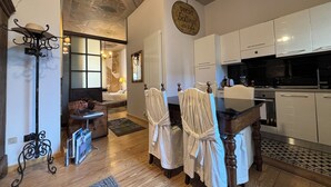 A modern kitchen with white cabinets, a dining table with chairs, and a chandelier. - Verona Journeys (Verona)