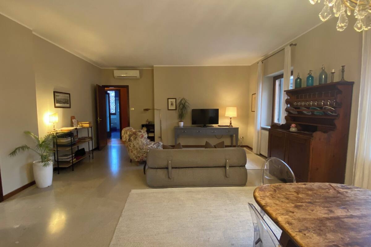 A living room with a sofa, a television, a dining table, and a chandelier.