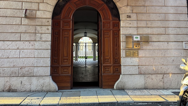 An arched entrance with a wooden door, a stone wall, and a number plaque. - Verona Journeys (Verona)