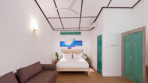 Ein Schlafzimmer mit einem Bett, Holzboden, einem braunen Sofa, einem Deckenventilator und einer grünen Tür.