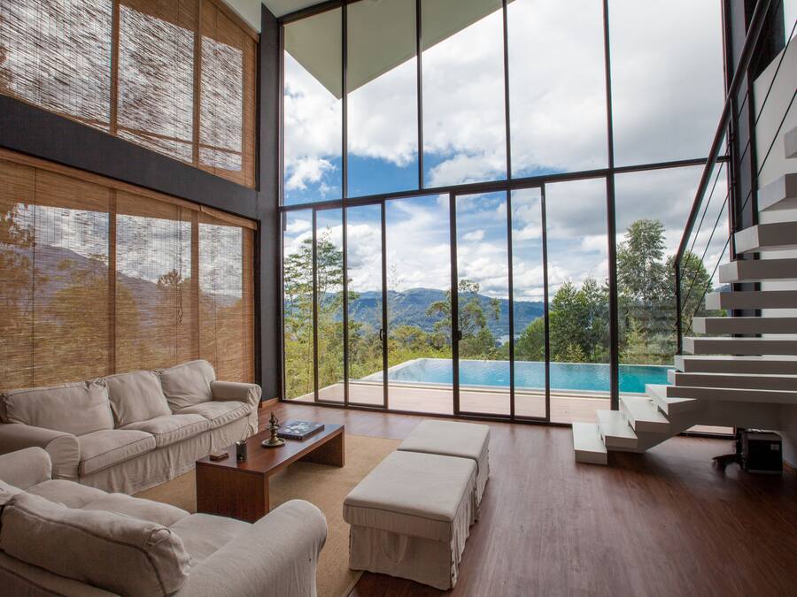 Uma sala de estar ampla com uma grande janela que oferece vista para uma piscina e montanhas.