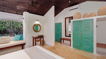 A bedroom with a bed, a desk, a chair, a bench, a mirror, and two green doors.