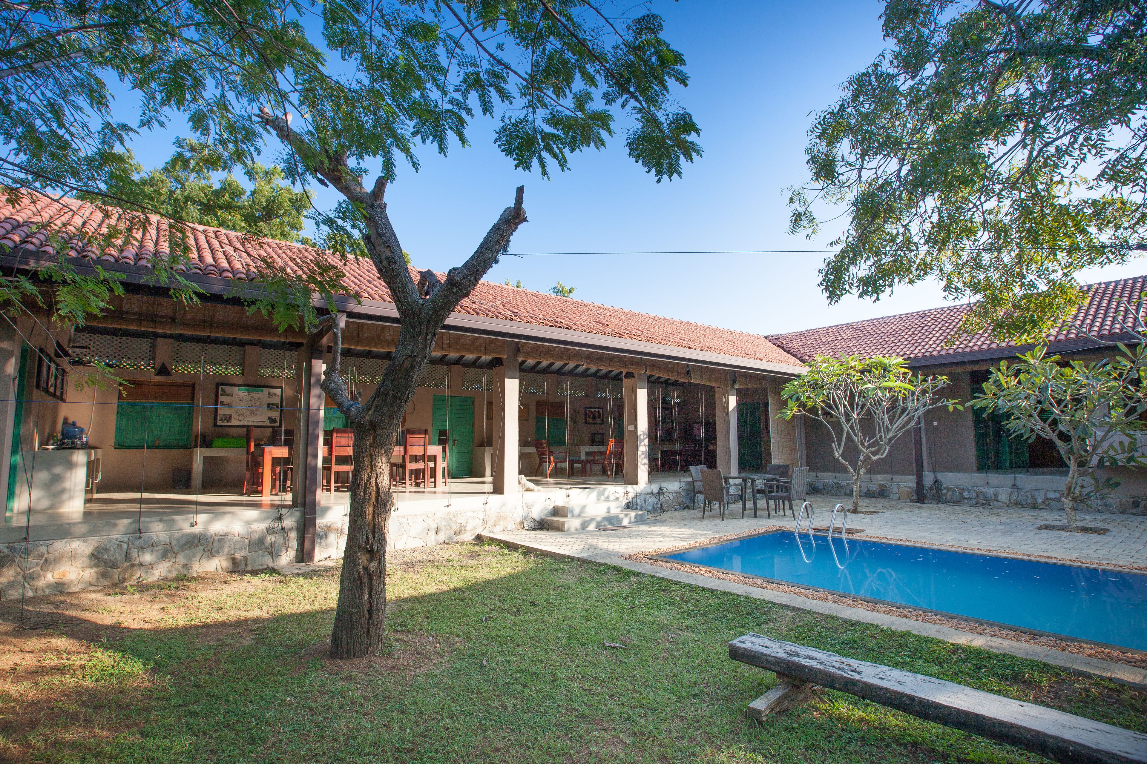 Una casa con piscina, terraza techada y un árbol en el jardín.