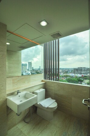 Ein modernes Badezimmer mit Waschbecken, Toilette und einem Fenster mit Blick auf die Stadt.