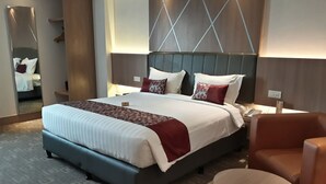 A modern hotel room with a large bed, a round table, and a seating area. - Demelia Hotel (Makassar)