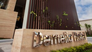 A hotel entrance with a vertical wooden facade and a sign that reads "Demelia Hotel". - Demelia Hotel (Makassar)