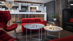 A modern hotel lobby with a reception desk, red seating, and a bar area. - Home Swiss Hotel (Geneva)