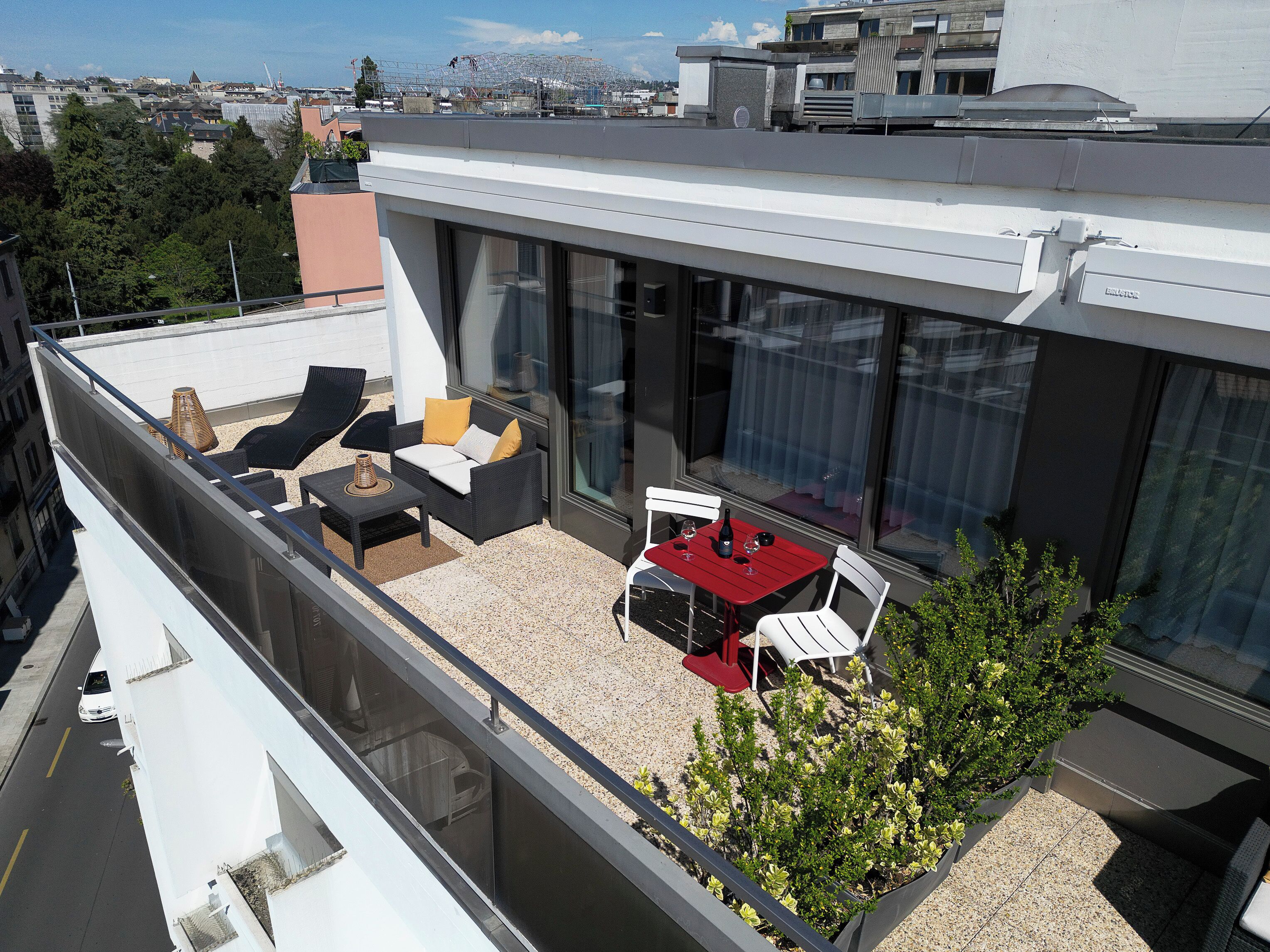 Une terrasse sur le toit, aménagée avec du mobilier d’extérieur, une table à manger et un petit espace jardin.