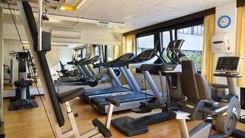 Een sportschool met meerdere loopbanden, elliptische trainers en een hometrainer.