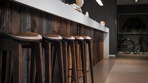 A bar area with wooden stools and a white countertop. - Home Swiss Hotel (Geneva)
