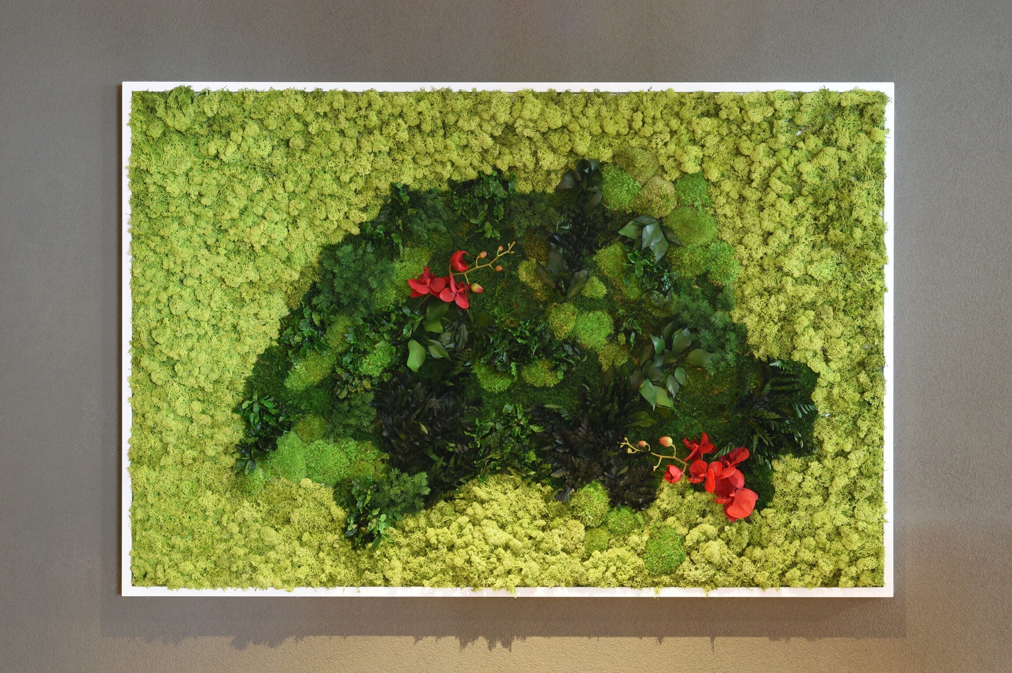 A rectangular wall with a moss-like texture and red flowers.