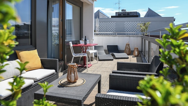 A rooftop terrace with wicker furniture, a table, and chairs. - Home Swiss Hotel (Geneva)