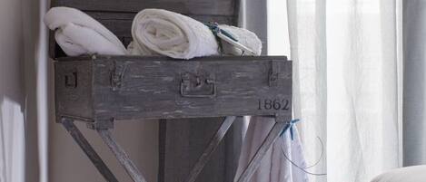 Un tendedero de madera con toallas, ubicado cerca de una ventana con cortinas.