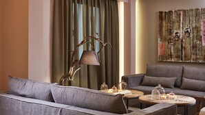 Uma sala de estar moderna com um sofá cinza, uma mesa de centro redonda de madeira e um abajur com design curvado.