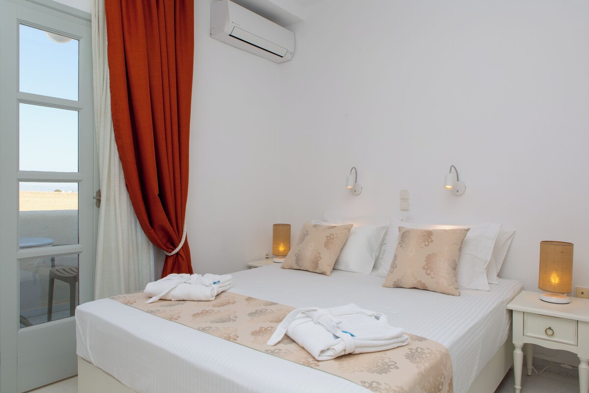 Habitación de hotel con cama, dos lámparas de noche, una mesita de noche y una ventana con cortinas.