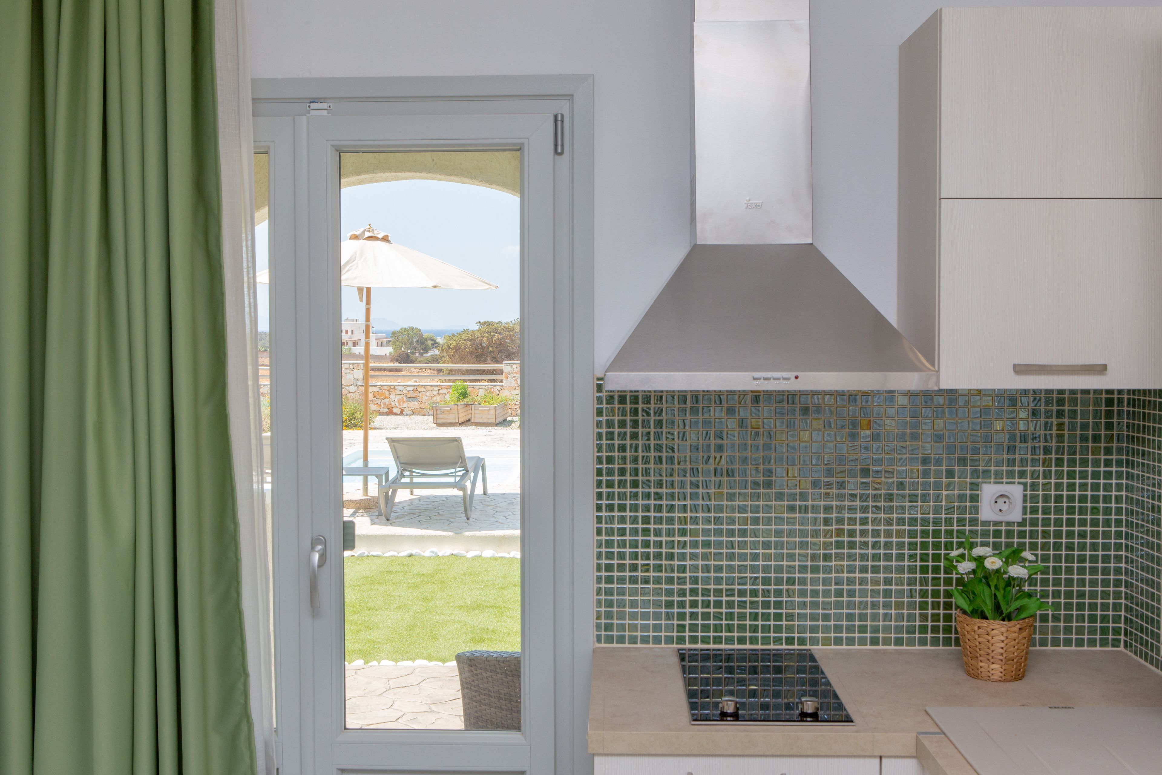 A kitchen with a view through a glass door to an outdoor patio area.