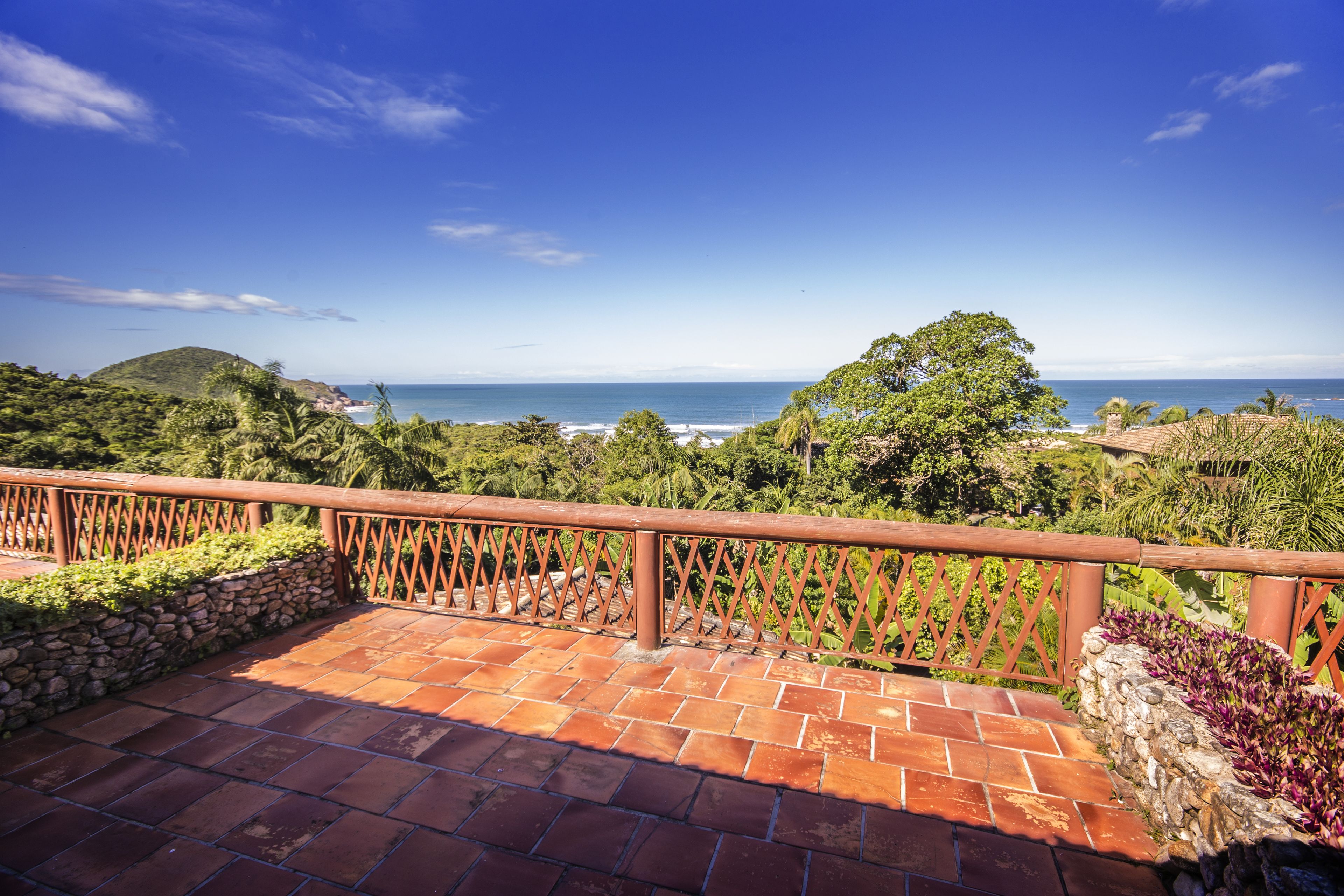 A terrace with a view of the ocean, stone walls, and a wooden railing.