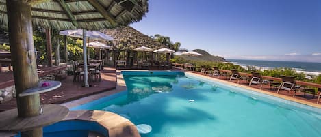 Una piscina al aire libre, sombrillas, sillones reclinables de piscina