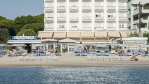 Ein mehrstöckiges Hotel mit Balkonen und einer Strandlage.