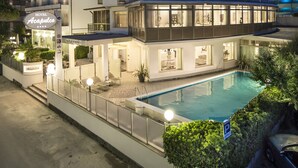 Ein mehrstöckiges Hotel mit Balkonen und einem Swimmingpool, mit einem Schild, das es als das Hotel A Capulco kennzeichnet.