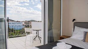 Ein Hotelzimmer mit Bett, kleinem Tisch, Stuhl und Balkon mit Blick.