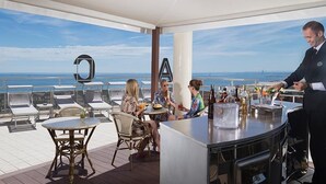 A deck with outdoor seating, a bar, and a view of the ocean. - Hotel Mocambo (Cervia)