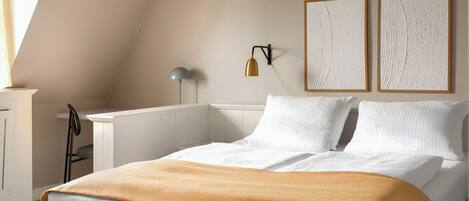 A bedroom with a bed, a desk, a chair, and two wall-mounted lamps.