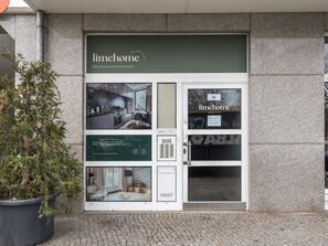 Ein limehome Apartment mit modernem Design, das ein großes Fenster und einen Blumentopf vor der Tür zeigt.