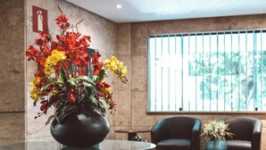 Un vestíbulo moderno con una mesa redonda que presenta un centro de flores, una alfombra estampada y un área de descanso con sillones de cuero.