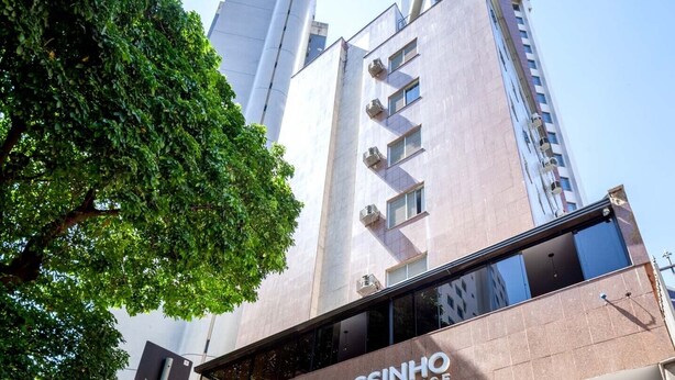 Fachada del hotel y residencia Savassiinho, con un diseño moderno, amplias ventanas y una entrada destacada.