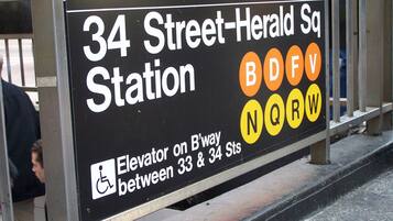 A sign for 34 Street-Herald Sq Station with an elevator on B-way between 33 & 34 Sts.