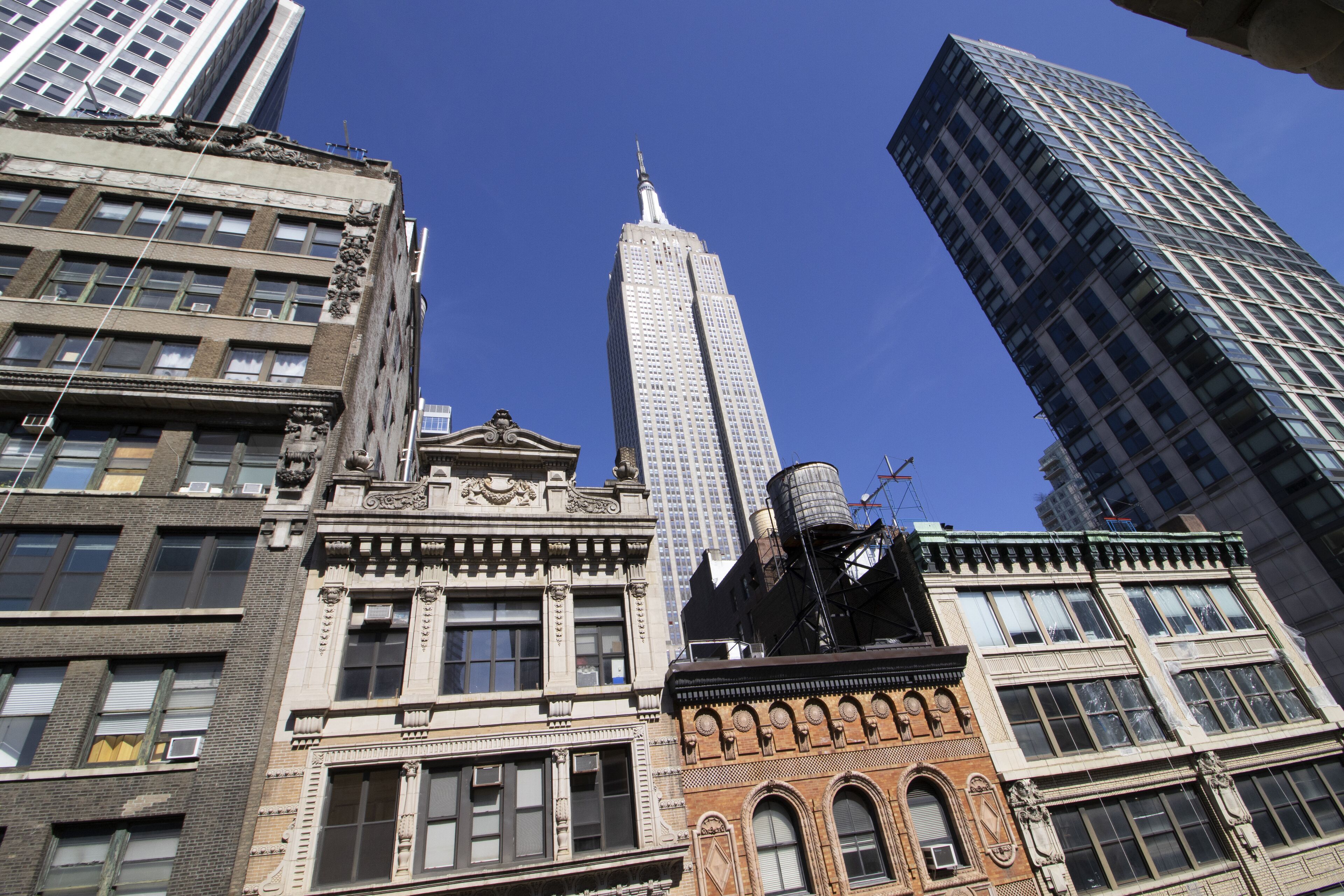 A high-rise building with a distinctive spire, surrounded by other tall buildings with various architectural styles.