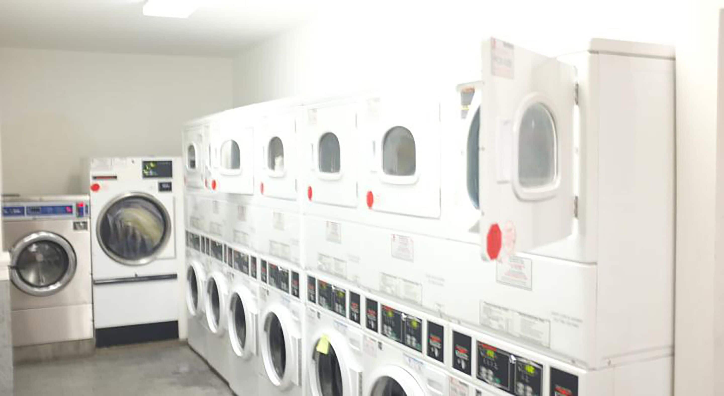 Une laverie équipée de plusieurs machines à laver et de plusieurs séchoirs.