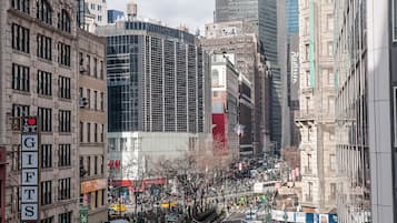A busy urban street with historic buildings, a modern glass structure, and various commercial signs.