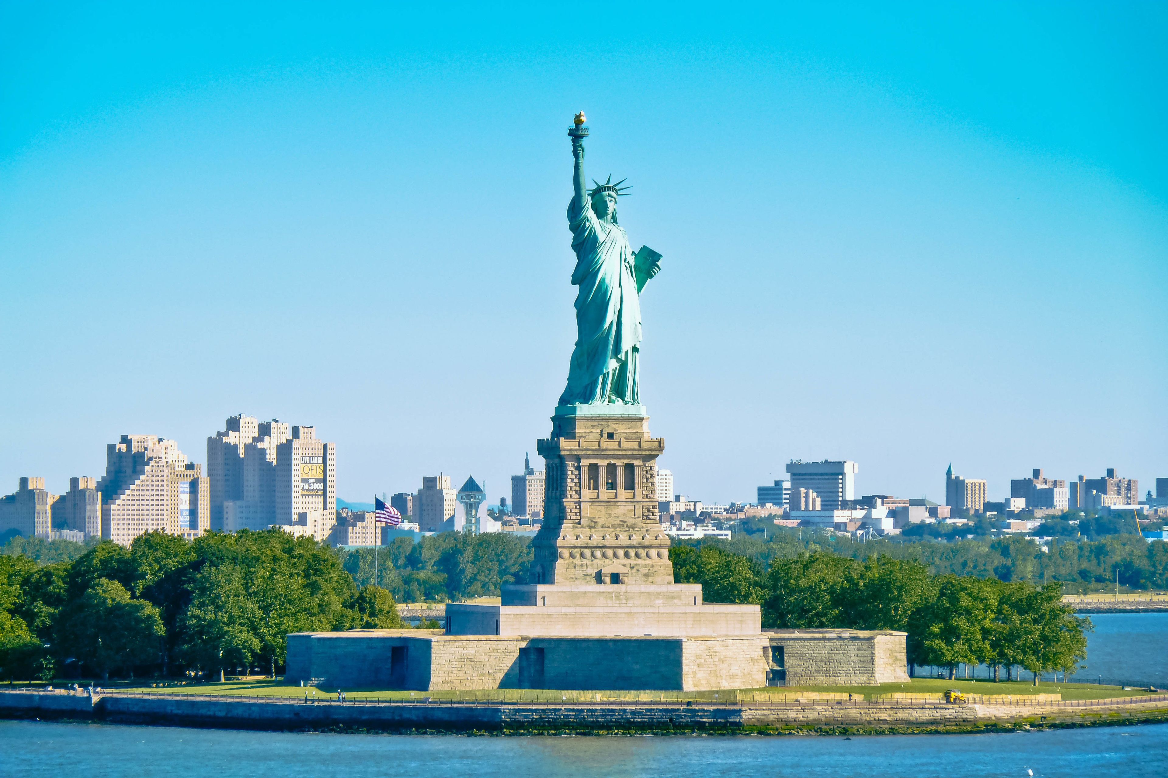 Die Freiheitsstatue in New York City, umgeben von Wasser und Stadtgebäuden.