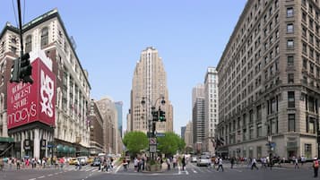 A busy urban street with tall buildings, including a prominent Macy's store.