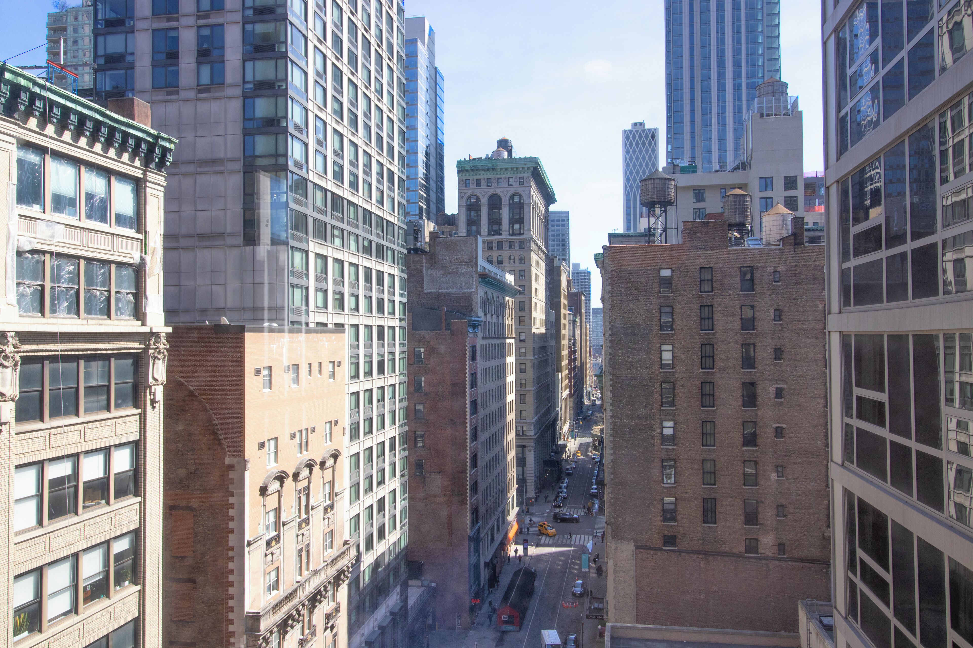 A cityscape with tall buildings, a street with vehicles, and a clear sky.