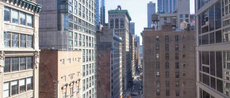 A cityscape with tall buildings, a street with vehicles, and a clear sky.
