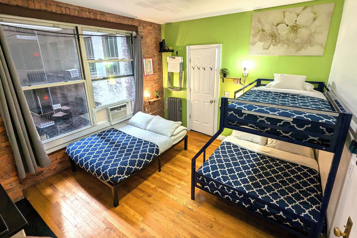 Ein Schlafsaalzimmer mit Etagenbett, Einzelbett und Fenster zum Innenhof.