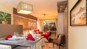 Un espace repas moderne avec une table en marbre, des serviettes rouges et un lustre.