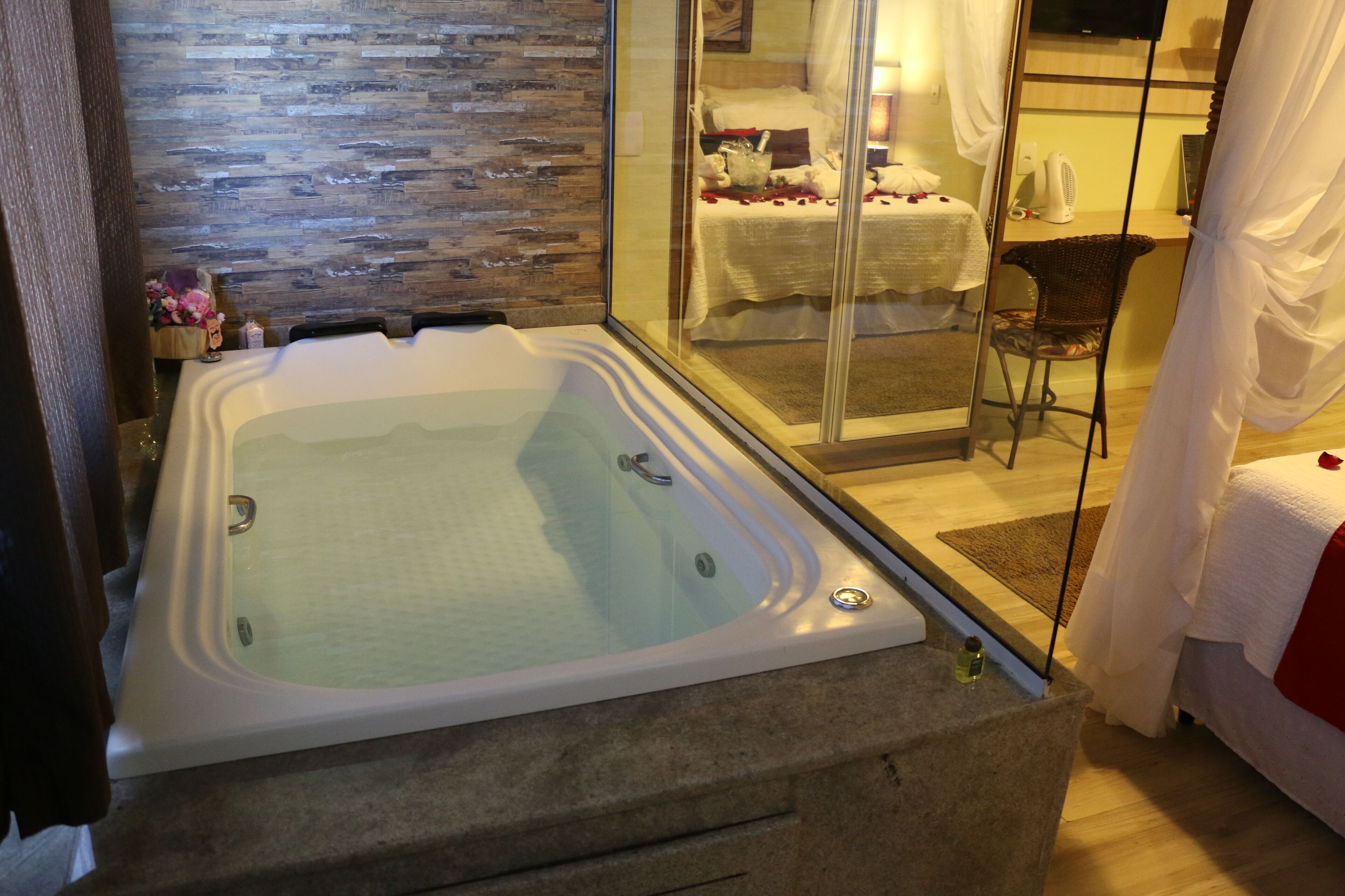 A modern bathroom with a large bathtub, a wooden wall, and a glass shower enclosure.