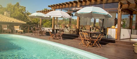 Una piscina al aire libre, sombrillas, sillones reclinables de piscina