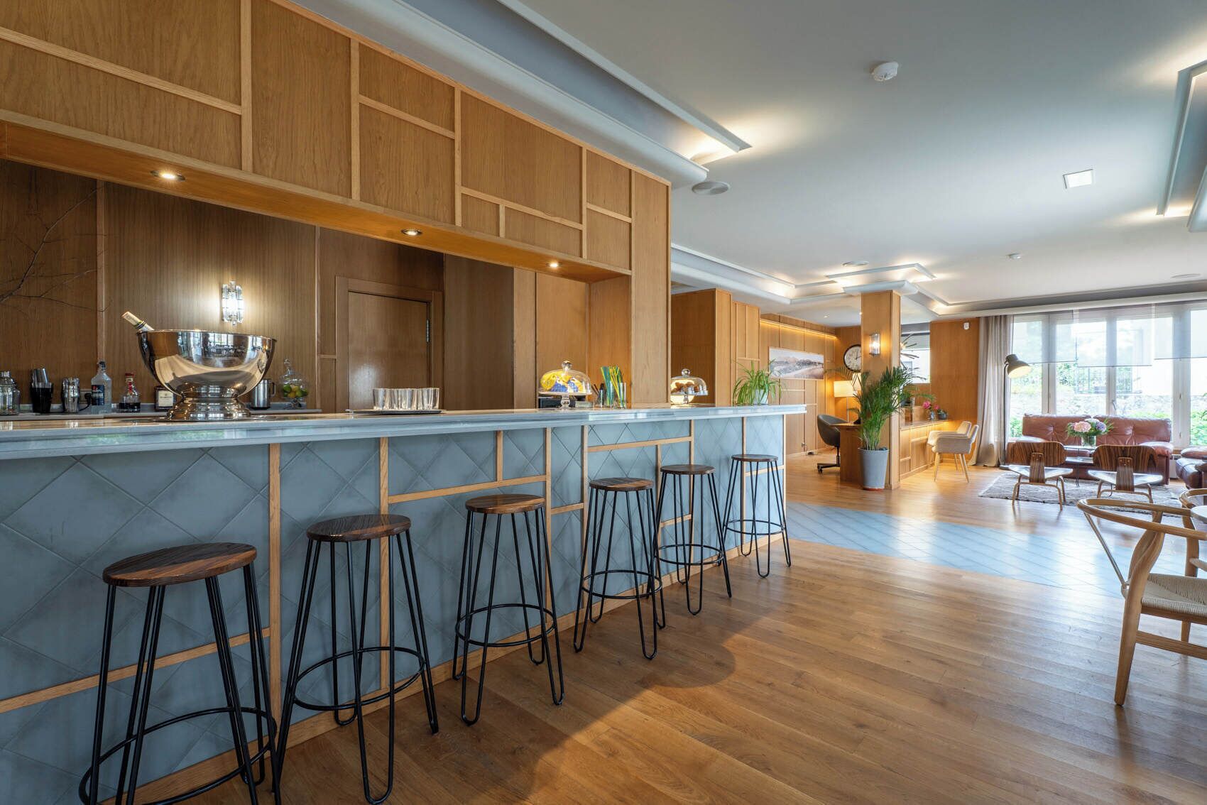 A modern kitchen with a bar area, wooden cabinetry, and bar stools.