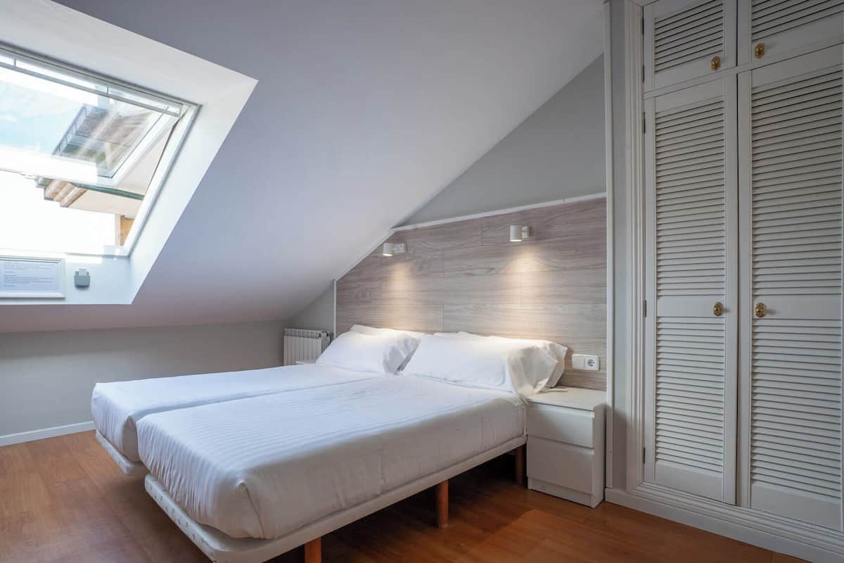 Ein Schlafzimmer mit Dachfenster, einem Bett, Nachttischen und einem Kleiderschrank.