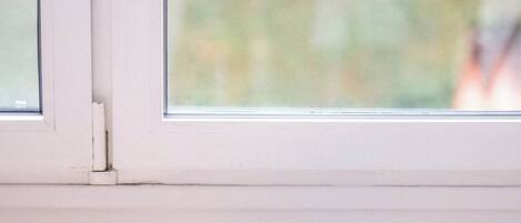 Una ventana con vista a la vegetación, un escritorio de madera y una carpeta azul con un bolígrafo encima.