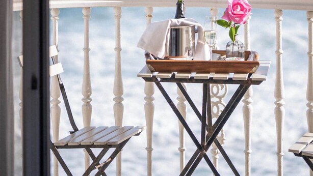 Un balcon avec une table dressée pour deux personnes, donnant sur l’océan.